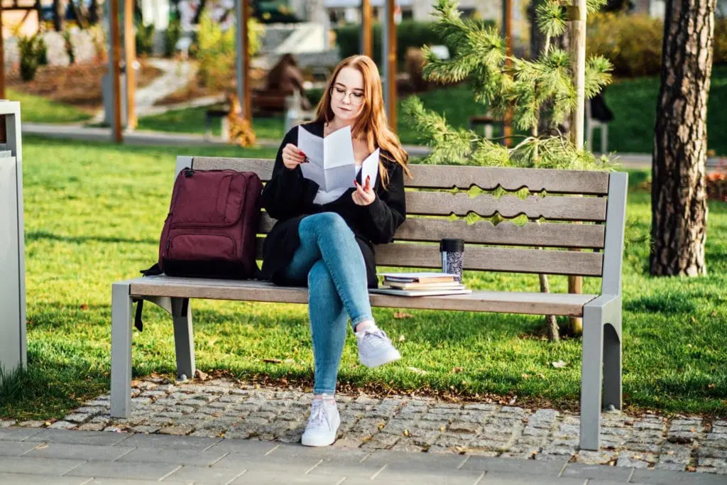 Student on a bench reading papers