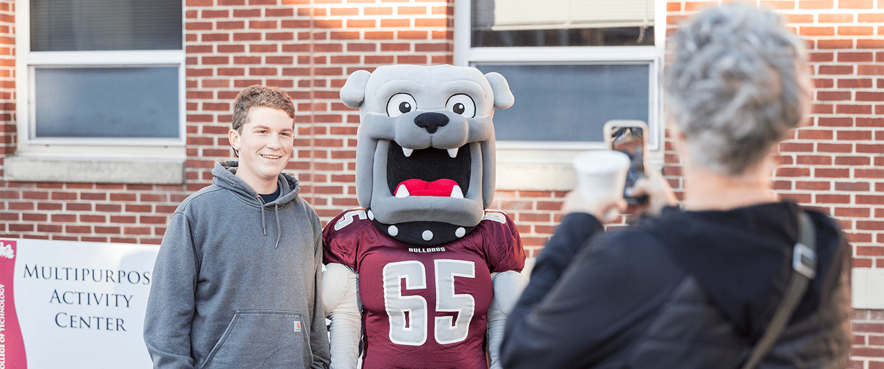 TSCT Student posing with Champ the Bulldog mascot outside of Multipurpose Activity Center (MAC)