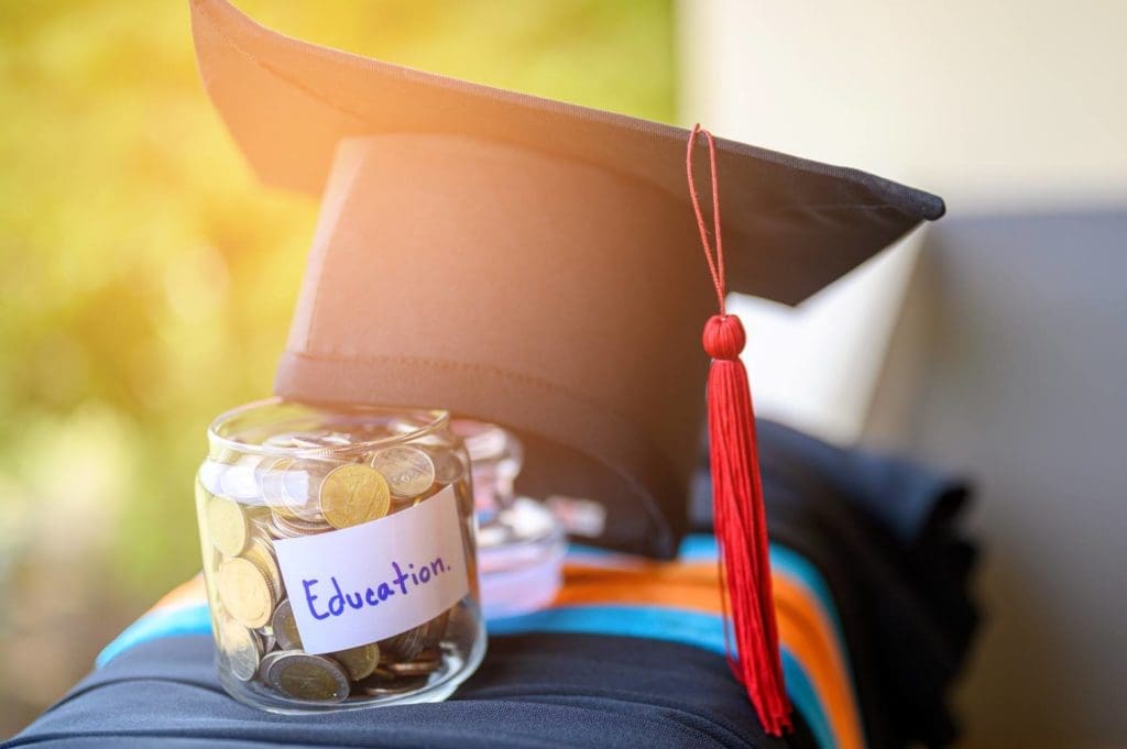 A jar of money with a graduation cap featured in the sunlight. 