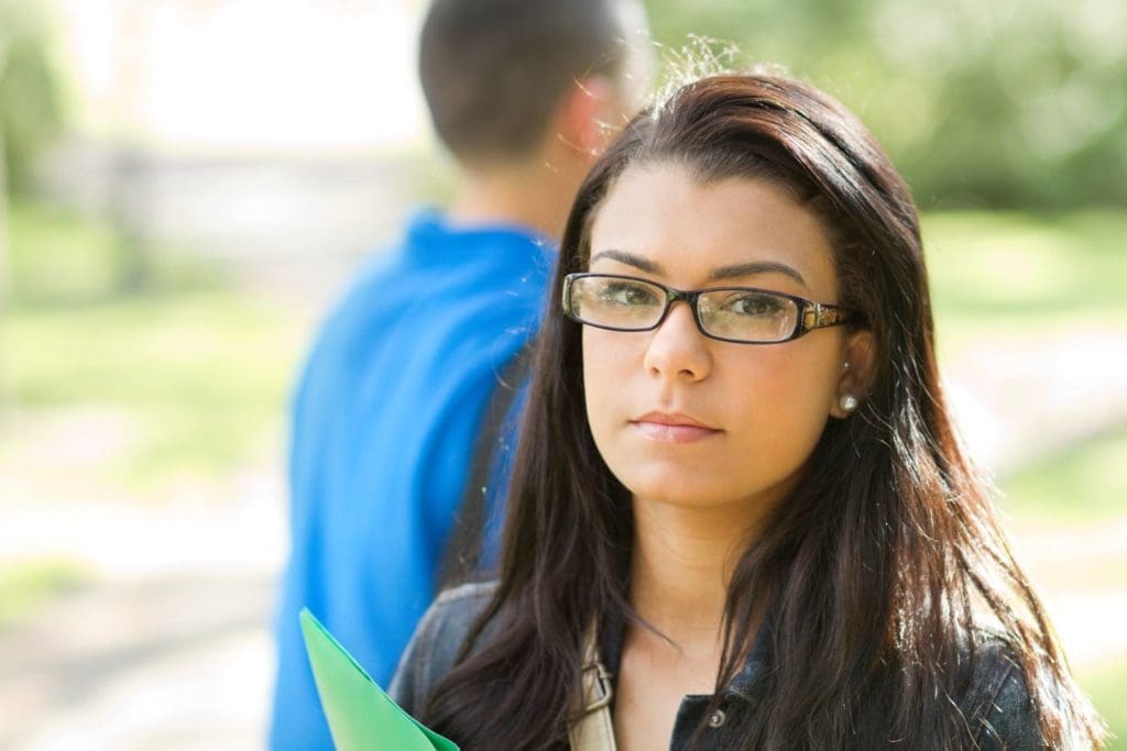 A student wearing glasses looks at the camera
