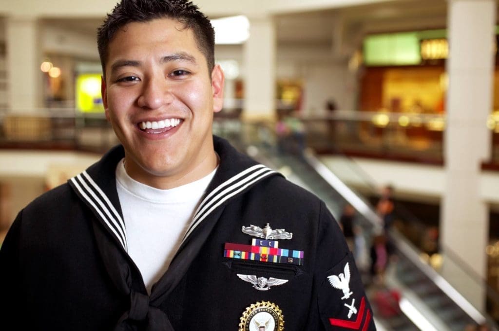 A member of the US navy smiling at the camera. 