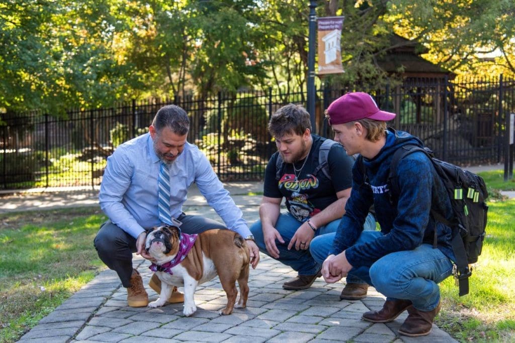 President Rivera, his bulldog Violet, and two students on the main campus
