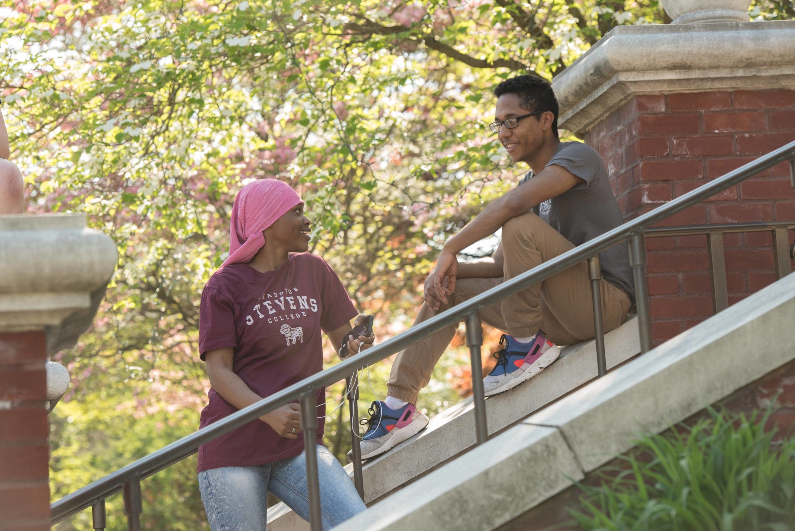 Students outside on a set of stairs talking. 