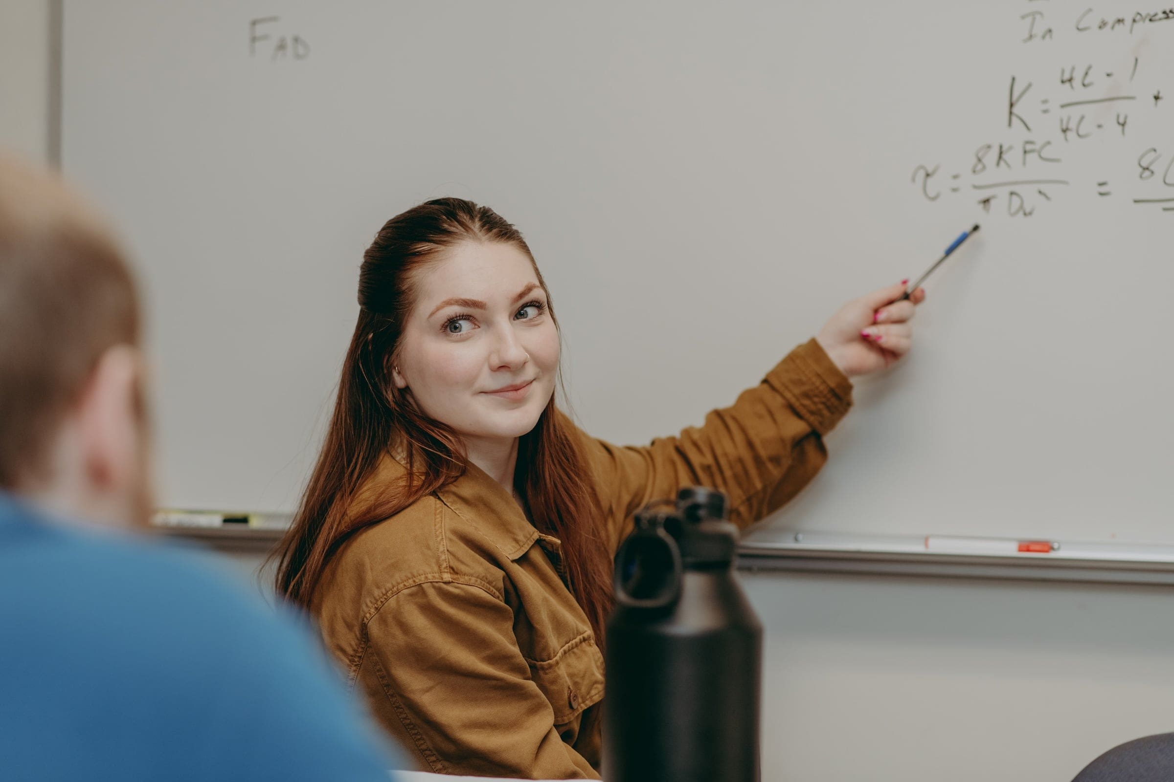 a student notates an equation on the board for her mechanical engineering class