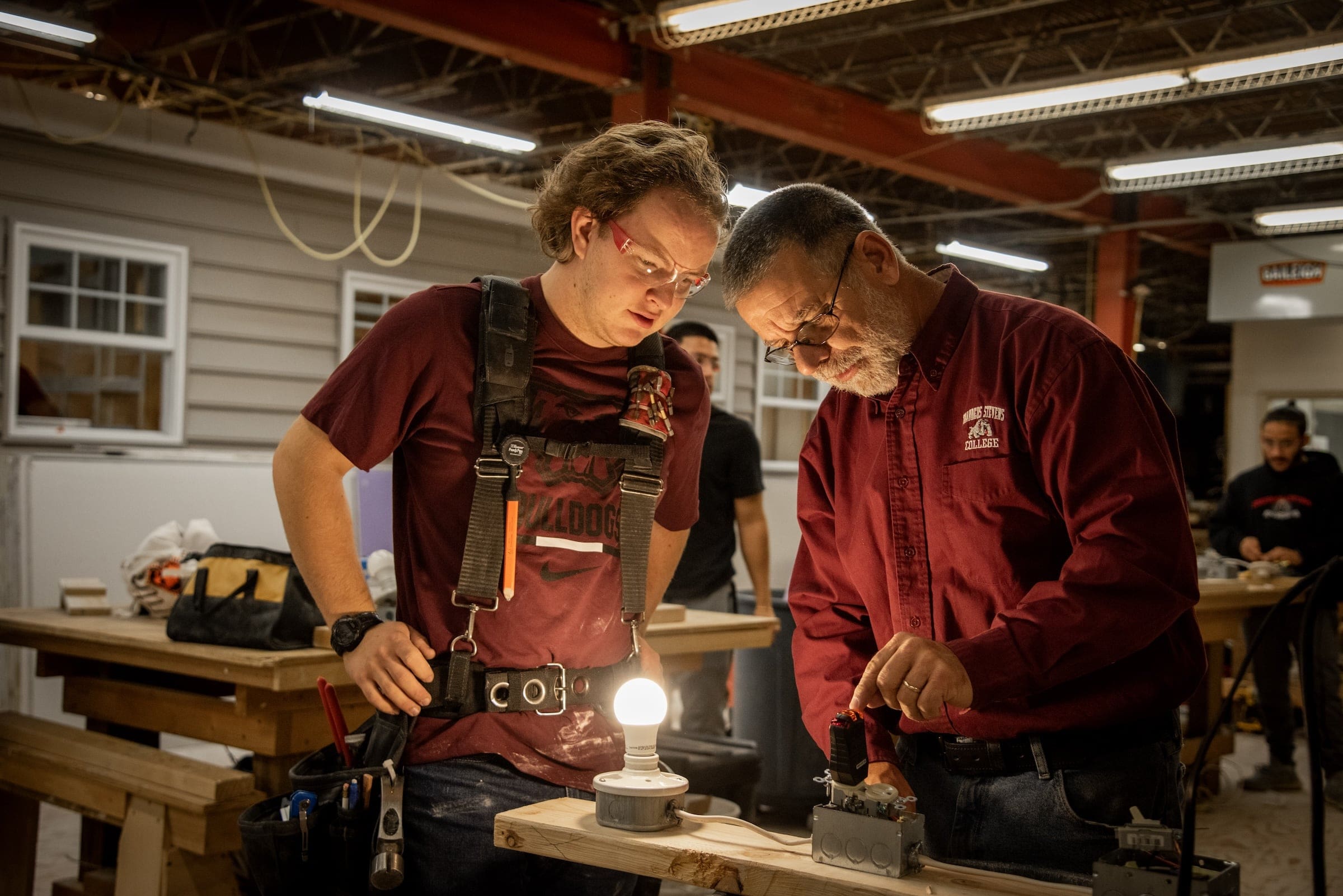 A residential remodeling instructor demonstrating electrical connections to a student.